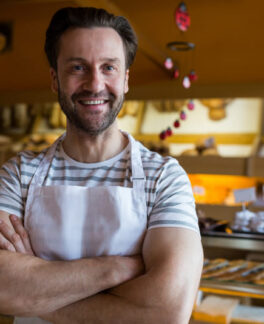 portrait-smiling-owner-standing-bakery-shop (2) (1)